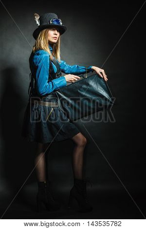 Journey and travel. Retro stylished girl with vintage big bag suitcase valise. Stylish victorian woman on dark background.