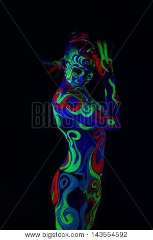 Nude girl with body art glowing in ultraviolet light