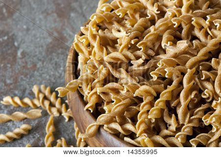 Skål af fuldkorn pasta spiraler eller fusilli over sten baggrund.
