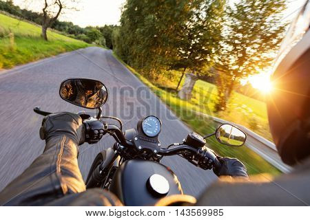 Motorcycle driver riding on motorway in beautiful sunset light. Shot from pillion driver view
