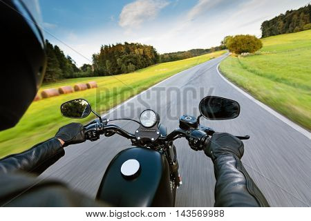 Motorcycle driver riding on motorway in beautiful sunset light. Shot from pillion driver view