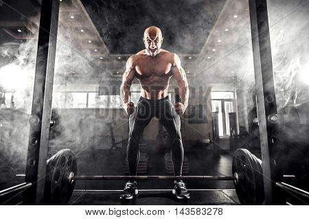 Athlete motivates screaming before barbells exercise at gym. Smoke