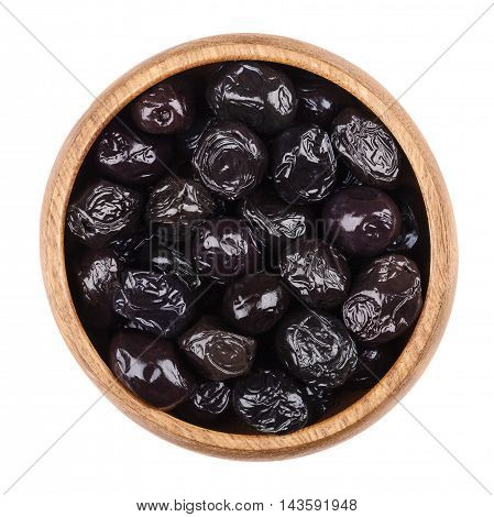 Black olives in a wooden bowl on white background. Dried ripe fruits of Olea europaea, one of the core ingredients in Mediterranean cuisine. Edible, raw, organic food. Isolated close up macro photo.