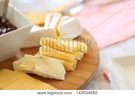 cheese platter with cherry preserves, grapes and various cheeses on a wooden board