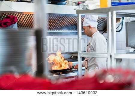 Chef or cook in hotel kitchen cooking dishes