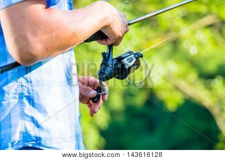 Close shot of sport fisherman reeling in the line on his fishing rod