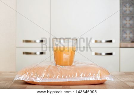 Plastic bag and glass full of apple juice on the wooden table