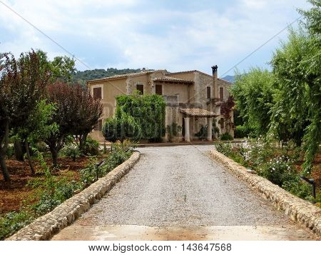 Pollenca Majorca Spain - June 28 2008: Finca vacation rental home - view from public street outside of the property - gate opened - driveway with garden in front