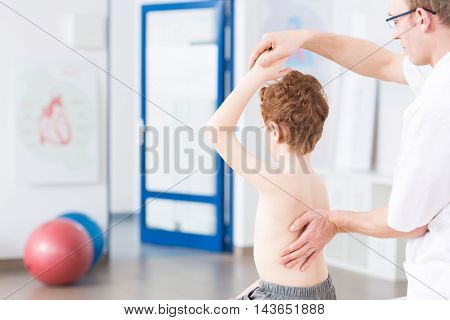 Physiotherapist during exercises with boy light interior