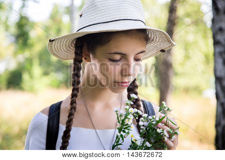 beautiful girl in straw hat with flowers in their hands