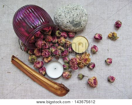 Dry roses flowers scattered on linen with candles