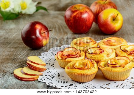 Apple shaped roses muffins on wooden background. Sweet apple dessert pie. Homemade apple rose pastry.