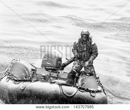 SOUTH GEORGIA, GREAT BRITAIN - NOV 9, 2012:  Unidentified man in a water proof suite in a rubber boat with a motor in the Atlantic Ocean. Atlantic Ocean is the world's second largest ocean