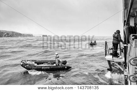 SOUTH GEORGIA, GREAT BRITAIN - NOV 9, 2012: Unidentified man goes down to get a place in a boat in the Atlantic Ocean. Atlantic Ocean is the world's second largest ocean