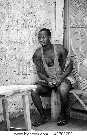 KARA, TOGO - MAR 9, 2013: Unidentified Togolese man sits on a bench. People in Togo suffer of poverty due to the unstable econimic situation