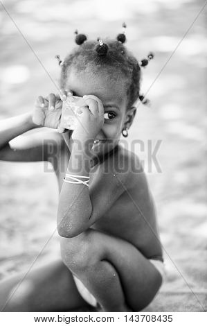 KARA, TOGO - MAR 9, 2013: Unidentified Togolese cute little girl in the street. Children in Togo suffer of poverty due to the unstable econimic situation