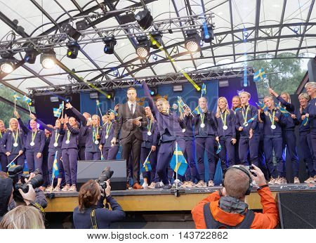 STOCKHOLM SWEDEN - AUG 21 2016: Happy swedish female soccer team waving swedish flags when the swedish olympic athletes are celebrated in Kungstradgarden, Stockholm, Sweden, August 21, 2016
