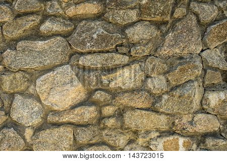 Wall of wild natural stone as background texture shot close-up.