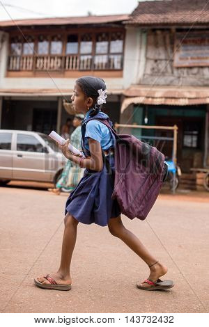 Gokarna, India - January 19, 2016: Unidentified indian girl with a heavy school bag go to school in Gokarna, India.