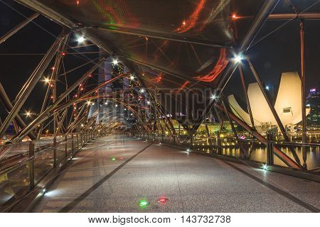 SINGAPORE SINGAPORE - SEPTEMBER 28 2013 : Night view of Helix bridge which leading to Marina Bay Sands luxury hotel a famous tourist attraction of Singapore.