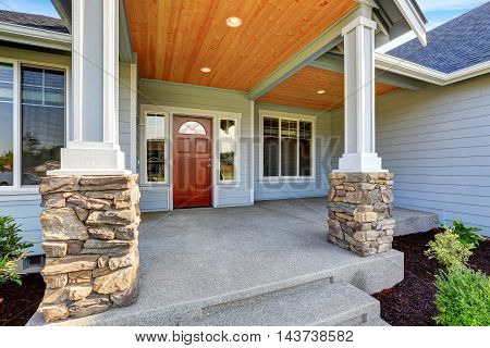 Light Blue Siding House . Porch With Stone Base Columns.