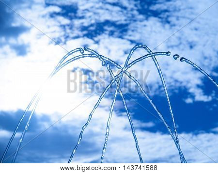 Fountain fresh water splash on hot summer sky background. Clear water or refreshment theme.