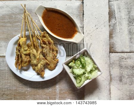 Pork satay dish on a wooden table .