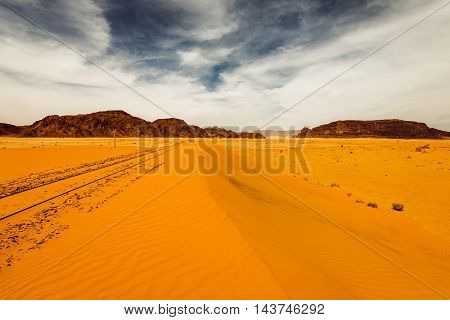 Sand dunes under dramatic sky with backfilled of sand railroad Wadi Rum Jordan. concept of global warming.
