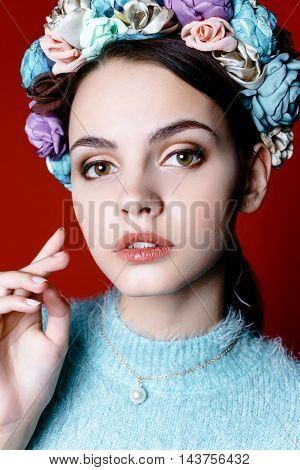 Beautiful model with a wreath of flowers on her head on red background