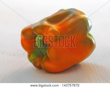 Ripening bell pepper. Paprika of orange and green color upon wooden background. Macro image. Selective focus.