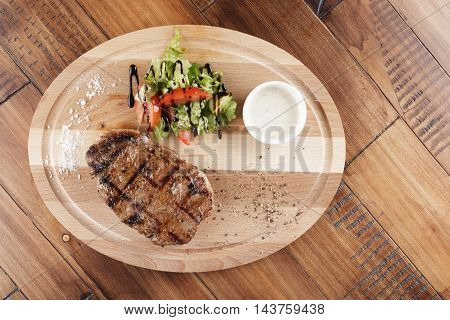 striploin steak with sauce on wooden surface. wooden background.