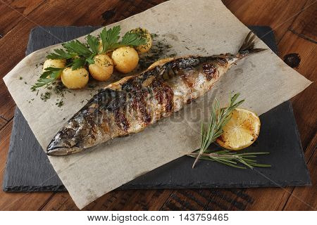 Mackerel fish fried with young potato on shale surface. wooden background