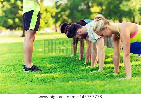 fitness, sport, friendship and healthy lifestyle concept - group of happy teenage friends or sportsmen exercising and doing push-ups at boot camp