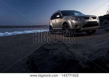 Saratov, Russia - November 27, 2014: Car Mitsubishi Outlander stay on ice coast at winter sunset