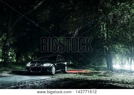 Saratov, Russia - June 12, 2015: Black car BMW E90 stand on road in darkness forest at night