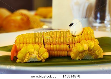 boiled corn car with carrot frontlights and quail egg driver close up photo on the plate