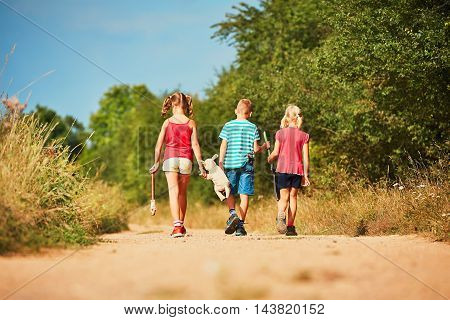 Siblings in nature. Two girls and one boy holding toys and going to play.