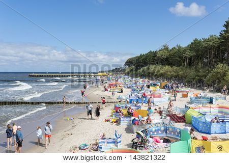 USTRONIE MORSKIE - AUGUST 15: Tourists enjoy the sunny weather and relaxing on the Baltic sea beach on 15 August 2016 in Ustronie Morskie, Poland.