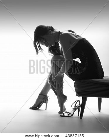 Beautiful sitting woman instudio with high heel shoes, white background