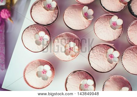 Pink cupcakes with flowers on the holiday table