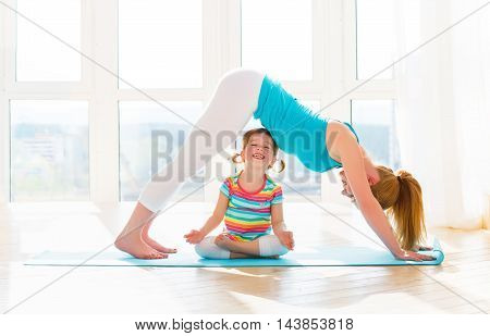 family mother and child daughter are engaged in fitness yoga exercise at home