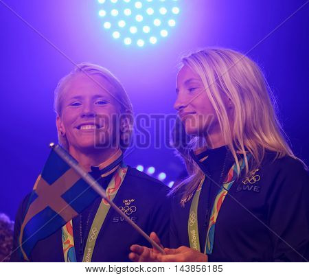 STOCKHOLM SWEDEN - AUG 21 2016: Happy swedish female wrestler Jenny Fransson and Sofia Mattson waiving a flag when swedish olympic athletes are celebrated in Kungstradgarden StockholmSwedenAugust 212016