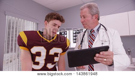 Young Adult Sports Athlete Looking At Sports Injury On Tablet Computer