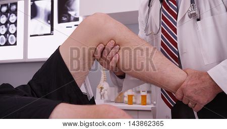 Senior caucasian doctor examining knee injury in the office