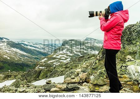 Tourism vacation and travel. Female tourist taking photo with camera enjoying mountains landscape from Dalsnibba viewpoint Norway Scandinavia.
