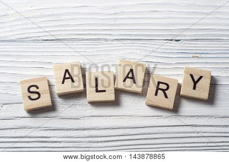 SALARY word written on wood block at wooden background