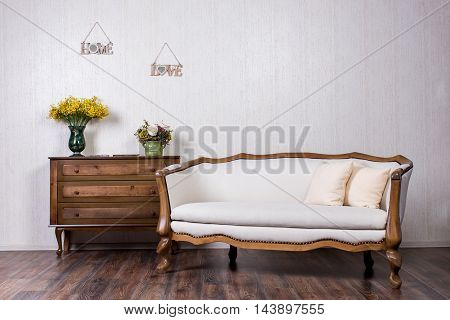 Coach and dresser in home inrerrior decorated with flovers and plates