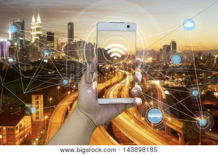 Hand holding white phone with city scape and wifi network connection concept