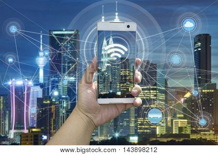 Hand holding white phone with city scape and wifi network connection concept