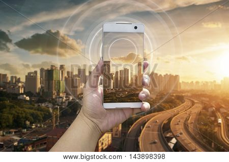 Hand holding white phone with city scape and wifi network connection concept .